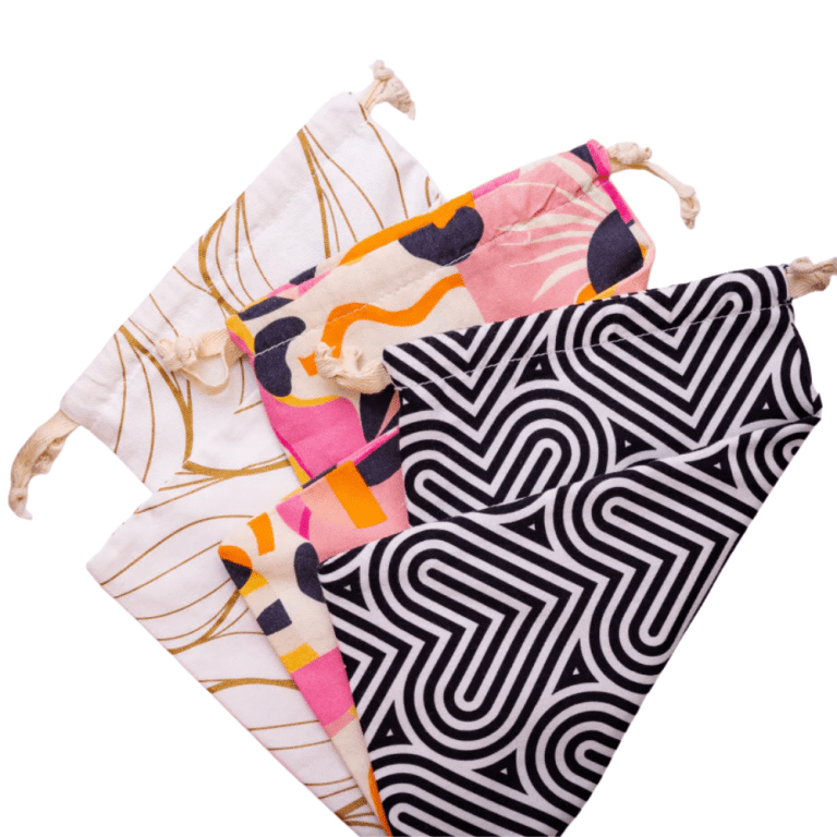3 cloth bags with different designs laying flat and folder over againts a white background