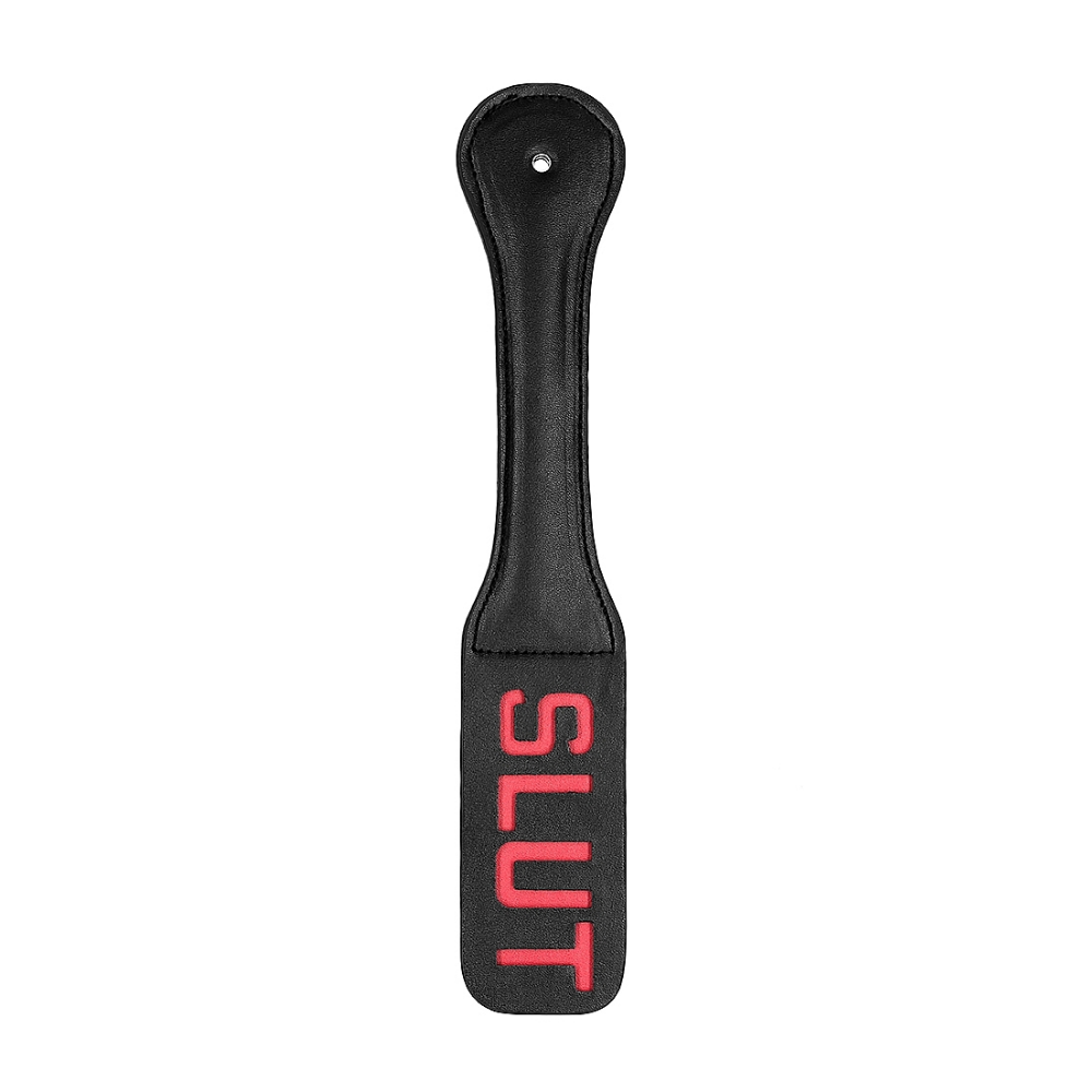 white background with black leather paddle with red cutout words spelling slut